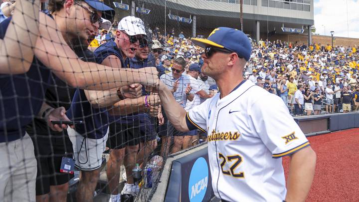 Jun 5, 2026; Morgantown, WV, USA; West Virginia Mountaineers head coach Steve Sabins celebrates with Pat McAfee in the stands after defeating the Cal Poly Mustangs at Kendrick Family Ballpark. Mandatory Credit: Ben Queen-Imagn Images Jun 5, 2026; Morgantown, WV, USA; West Virginia Mountaineers head coach Steve Sabins celebrates with Pat McAfee in the stands after defeating the Cal Poly Mustangs at Kendrick Family Ballpark. Mandatory Credit: Ben Queen-Imagn Images