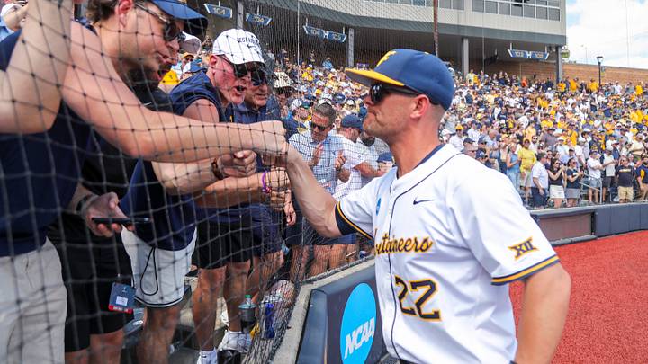 Jun 5, 2026; Morgantown, WV, USA; West Virginia Mountaineers head coach Steve Sabins celebrates with Pat McAfee in the stands after defeating the Cal Poly Mustangs at Kendrick Family Ballpark. Mandatory Credit: Ben Queen-Imagn Images
