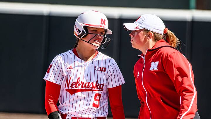 Hannah Camenzind (9) chats with assistant coach Olivia Ferrell after a single. 
