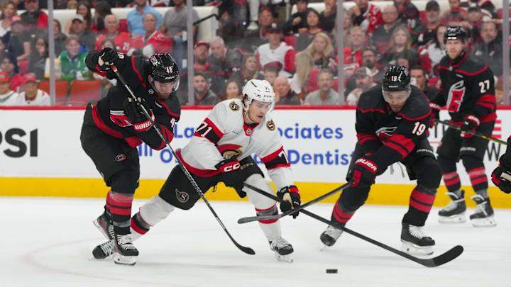 Apr 18, 2026; Raleigh, North Carolina, USA; Ottawa Senators center Ridly Greig (71) tries to skate with the puck past Carolina Hurricanes left wing Jordan Martinook (48) and defenseman K'andre Miller (19) during the second period in game one of the first round of the 2026 Stanley Cup Playoffs at Lenovo Center. Mandatory Credit: James Guillory-Imagn Images