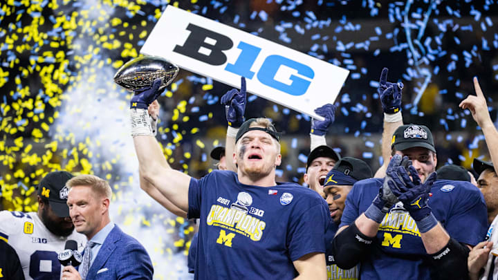 Dec 4, 2021; Indianapolis, IN, USA; Michigan Wolverines defensive end Aidan Hutchinson (97) lifts the Big Ten Championship Trophy after the game against the Iowa Hawkeyes  at Lucas Oil Stadium. Mandatory Credit: Trevor Ruszkowski-Imagn Images