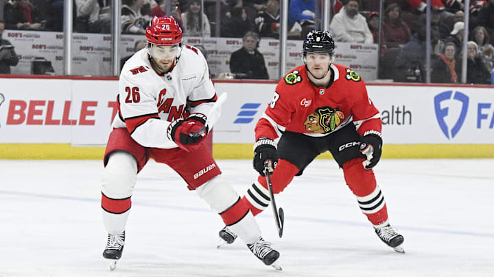 Jan 20, 2025; Chicago, Illinois, USA;  Carolina Hurricanes defenseman Sean Walker (26) moves the puck against Chicago Blackhawks center Ryan Donato (8) during the first period at the United Center. Mandatory Credit: Matt Marton-Imagn Images


