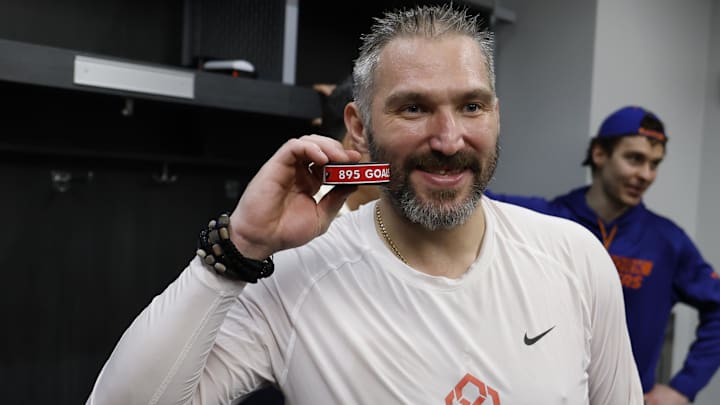 Washington Capitals left wing Alex Ovechkin poses with the puck as he celebrates after scoring his record-setting 895th goal.