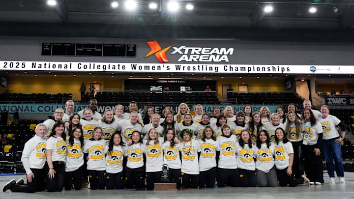 Iowa wrestlers and coaches pose with their first-place team trophy at the National Collegiate Women’s Wrestling Championship finals Saturday, March 8, 2025 at Xtream Arena in Coralville, Iowa.