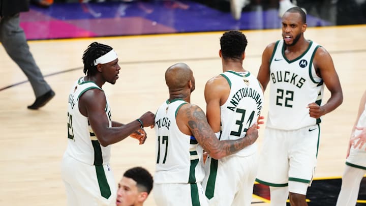 Jul 17, 2021; Phoenix, Arizona, USA; Milwaukee Bucks forward P.J. Tucker (17) celebrates with forward Giannis Antetokounmpo (34), guard Jrue Holiday (21) and forward Khris Middleton (22) as Phoenix Suns guard Devin Booker (1) walks off the court following game five of the 2021 NBA Finals at Phoenix Suns Arena. Mandatory Credit: Mark J. Rebilas-Imagn Images