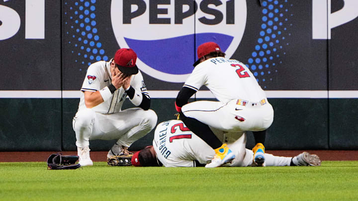 Sep 1, 2025; Phoenix, Arizona, USA;  Arizona Diamondbacks outfielder Lourdes Gurriel Jr. (12) is attended to by his teammates after his injury in the sixth inning during the game between the Texas Rangers and Arizona Diamondbacks at Chase Field. Mandatory Credit: Arianna Grainey-Imagn Images