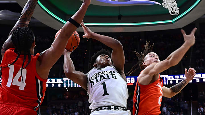 Jan 19, 2025; East Lansing, Michigan, USA;  Michigan State Spartans guard Jeremy Fears Jr. (1) splits Illinois Fighting Illini guard Kylan Boswell (14) and Illinois Fighting Illini guard Dra Gibbs-Lawhorn (2) on his way to a basket during the second half  at Jack Breslin Student Events Center. Mandatory Credit: Dale Young-Imagn Images