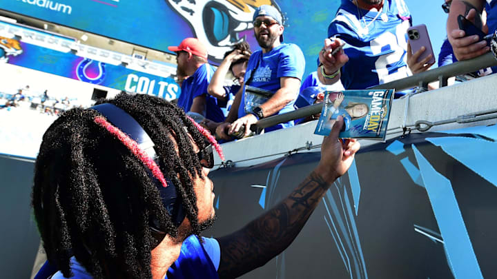 Indianapolis Colts quarterback Anthony Richardson (5), with his injured arm in a sling, hands back a game day program with a photo of Jacksonville Jaguars quarterback Trevor Lawrence (16) on the cover after autographing it for a fan ahead of Sunday's game. The Jacksonville Jaguars hosted the Indianapolis Colts at EverBank Stadium in Jacksonville, FL Sunday, October 15, 2023. [Bob Self/Florida Times-Union]