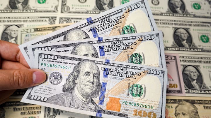 In this photo illustration, a hand holds several new $100 US... In this photo illustration, a hand holds several new $100 US...