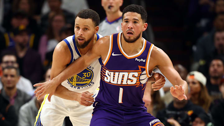 Dec 18, 2025; Phoenix, Arizona, USA; Phoenix Suns guard Devin Booker (1) against Golden State Warriors guard Stephen Curry (30) in the first half at Mortgage Matchup Center. Mandatory Credit: Mark J. Rebilas-Imagn Images
