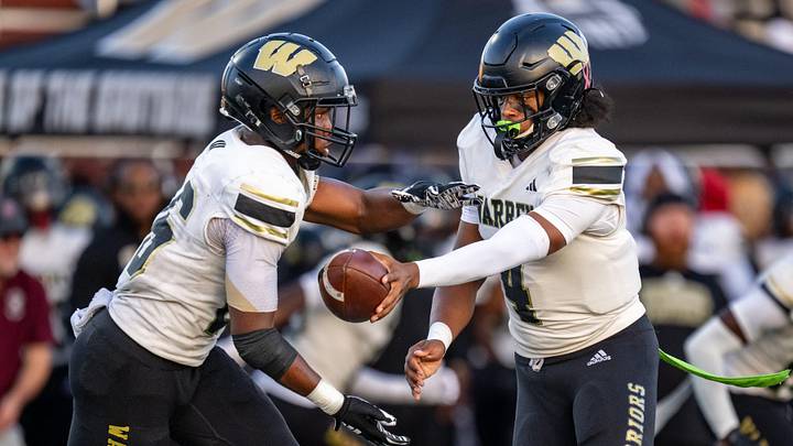 Warren Central High School junior Joe Goss (4) hands the ball off to senior Keyon Thomas (26) during the first half of an IHSAA varsity football game, Friday, Sept. 12, 2025, at Lawrence Central High School.