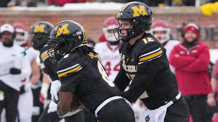 Nov 30, 2024; Columbia, Missouri, USA; Missouri Tigers quarterback Brady Cook (12) hands off to running back Nate Noel (8) against the Arkansas Razorbacks during the first half at Faurot Field at Memorial Stadium. Mandatory Credit: Denny Medley-Imagn Images