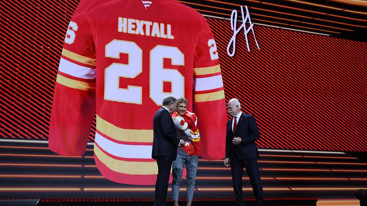Jun 26, 2026; Buffalo, New York, USA; Jack Hextall reacts beside NHL commissioner Gary Bettman and former NHL player Lanny McDonald after being selected with the thirtieth pick in the first round of the 2026 NHL Draft by the Calgary Flames at KeyBank Center. Mandatory Credit: Timothy T. Ludwig-Imagn Images
