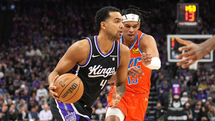 Dec 14, 2023; Sacramento, California, USA; Sacramento Kings forward Trey Lyles (left) dribbles against Oklahoma City Thunder forward Ousmane Dieng (right) during the first quarter at Golden 1 Center. Mandatory Credit: Darren Yamashita-Imagn Images