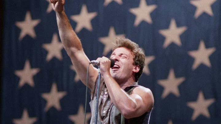 Bruce Springsteen singing onstage in front of American flag Bruce Springsteen singing onstage in front of American flag