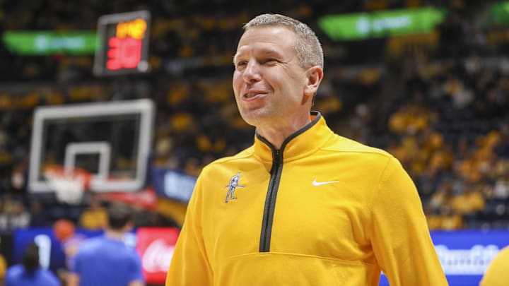Nov 13, 2025; Morgantown, West Virginia, USA; West Virginia Mountaineers head coach Ross Hodge smiles during pregame introductions before their game against the Pittsburgh Panthers at WVU Coliseum. Mandatory Credit: Ben Queen-Imagn Images Nov 13, 2025; Morgantown, West Virginia, USA; West Virginia Mountaineers head coach Ross Hodge smiles during pregame introductions before their game against the Pittsburgh Panthers at WVU Coliseum. Mandatory Credit: Ben Queen-Imagn Images