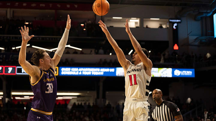 Cincinnati Bearcats guard Kerr Kriisa (11) hits a 3-point basket over Lipscomb Bisons guard Ross Candelino (30) in the first half of the NCAA basketball game at Fifth Third Arena in Cincinnati on Dec. 29, 2025.
