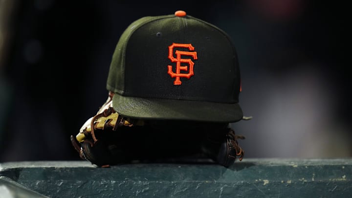 A San Francisco Giants hat sits on top of a glove on top of a dugout railing. A San Francisco Giants hat sits on top of a glove on top of a dugout railing.
