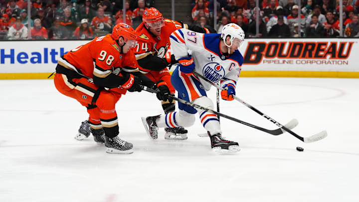 Apr 30, 2026; Anaheim, California, USA; Edmonton Oilers center Connor McDavid (97) handles the puck against Anaheim Ducks defenseman Pavel Mintyukov (98) and defenseman John Carlson (74) in the first period of game six of the first round of the 2026 Stanley Cup Playoffs at Honda Center. Mandatory Credit: Kirby Lee-Imagn Images