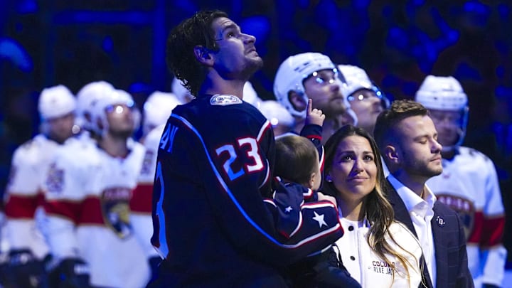 Columbus Blue Jackets center Sean Monahan holds Johnny Gaudreau’s child alongside Meredith Gaudreau and family.