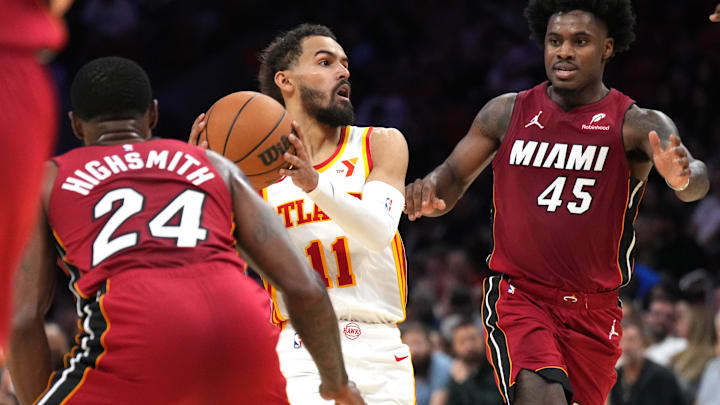 Feb 26, 2025; Miami, Florida, USA;  Atlanta Hawks guard Trae Young (11) lobs the ball toward the basket as Miami Heat guard Davion Mitchell (45) and forward Haywood Highsmith (24) close in during the second half at Kaseya Center. Mandatory Credit: Jim Rassol-Imagn Images