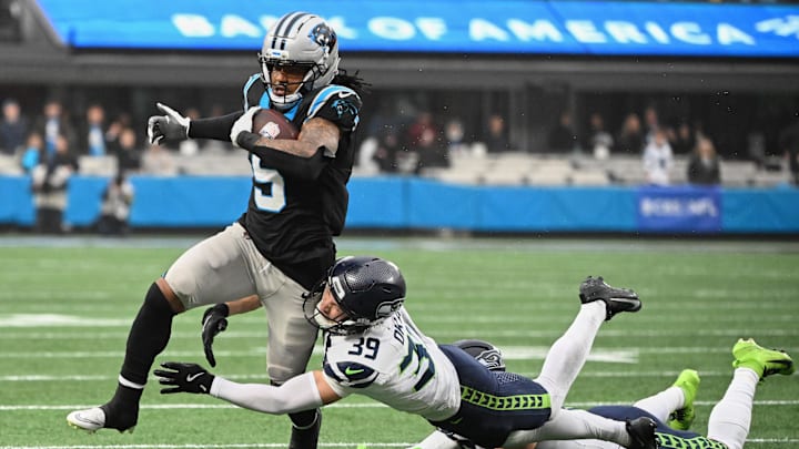 Dec 28, 2025; Charlotte, North Carolina, USA; Carolina Panthers running back Rico Dowdle (5) runs the ball against Seattle Seahawks safety Ty Okada (39) and linebacker Drake Thomas (42) (obscured) during the second quarter at Bank of America Stadium. Mandatory Credit: Bob Donnan-Imagn Images