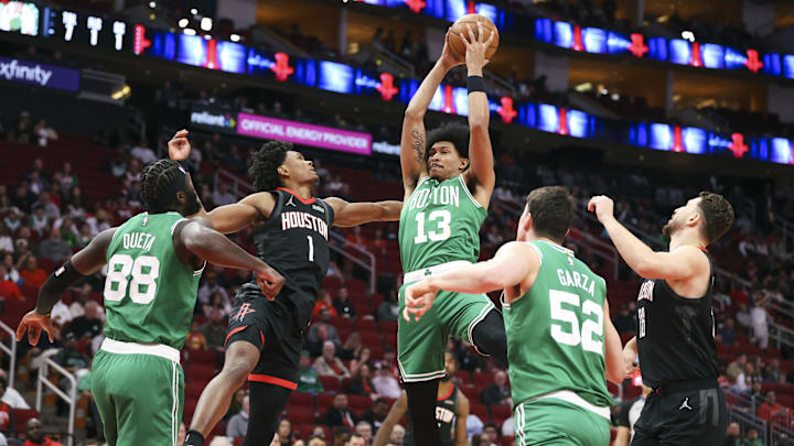 Feb 4, 2026; Houston, Texas, USA; Boston Celtics guard Ron Harper Jr. (13) grabs a rebound away from Houston Rockets guard Amen Thompson (1) during the first quarter at Toyota Center. Mandatory Credit: Troy Taormina-Imagn Images