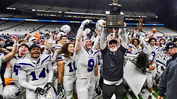 Longtime Sumner coach Keith Ross hoists the trophy after his Spartans won the WIAA Class 4A championship with a 27-24 victory over Camas on Saturday night.