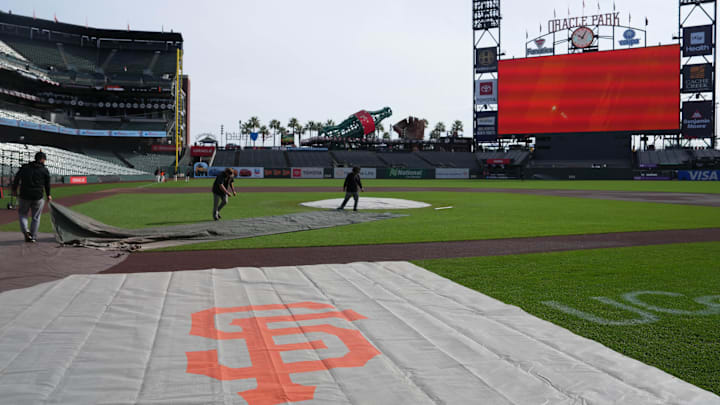 Mar 27, 2026; San Francisco, California, USA; Groundskeepers work as a tarp with the San Francisco Giants logo is laid out on the field before the game against the New York Yankees at Oracle Park. Mandatory Credit: Darren Yamashita-Imagn Images Mar 27, 2026; San Francisco, California, USA; Groundskeepers work as a tarp with the San Francisco Giants logo is laid out on the field before the game against the New York Yankees at Oracle Park. Mandatory Credit: Darren Yamashita-Imagn Images