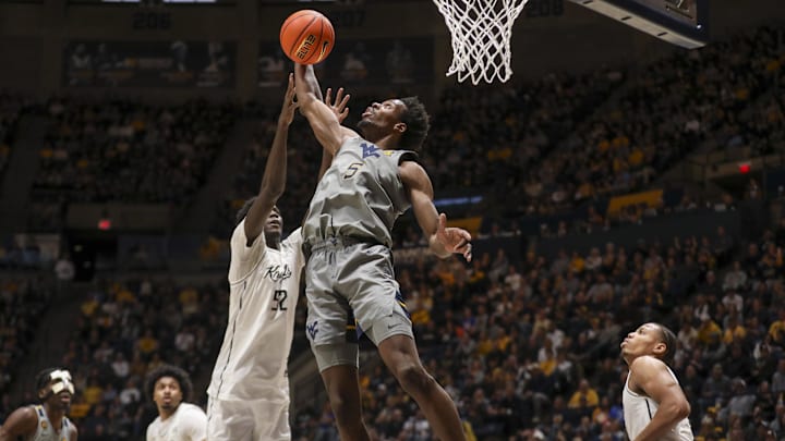 Mar 8, 2025; Morgantown, West Virginia, USA; West Virginia Mountaineers guard Toby Okani (5) grabs a rebound against UCF Knights center Moustapha Thiam (52) during the first half at WVU Coliseum. Mandatory Credit: Ben Queen-Imagn Images