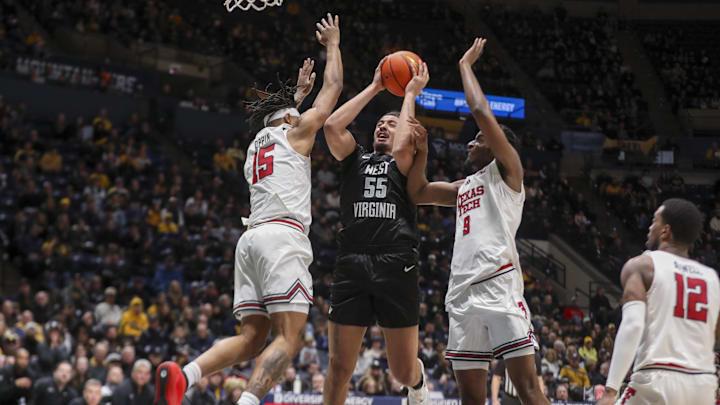 Feb 8, 2026; Morgantown, West Virginia, USA; West Virginia Mountaineers center Harlan Obioha (55) shoots in the lane against Texas Tech Red Raiders forward JT Toppin (15) and Texas Tech Red Raiders forward Luke Bamgboye (9) during the second half at Hope Coliseum. Mandatory Credit: Ben Queen-Imagn Images