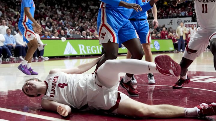 Jan 14, 2025; Tuscaloosa, AL, USA;  Alabama forward Grant Nelson (4) hits the floor hard after being fouled by Ole Miss forward Malik Dia (0) at Coleman Coliseum. Mandatory Credit: Gary Cosby Jr.-USA TODAY Network via Imagn Images