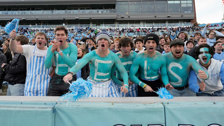 Nov 30, 2024; Chapel Hill, North Carolina, USA; North Carolina Tar Heels fans with Heels painted on their chest cheer in the first quarter at Kenan Memorial Stadium. Mandatory Credit: Bob Donnan-Imagn Images