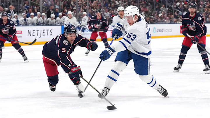 Blue Jackets defenseman Denton Mateychuk tries to break up Maple Leafs forward Easton Cowan's shot. 