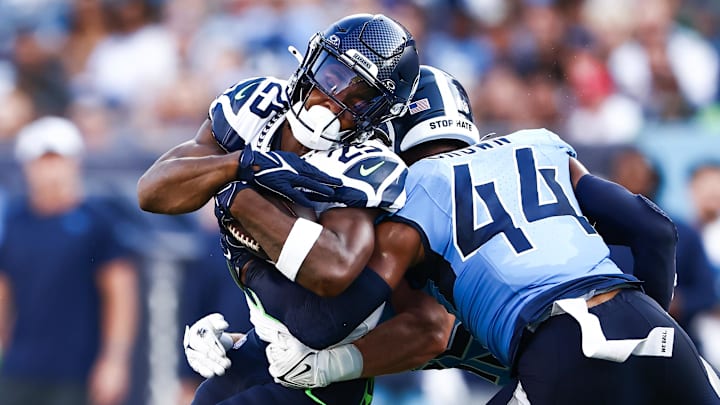 Aug 17, 2024; Nashville, Tennessee, USA; Seattle Seahawks running back Kenny McIntosh (25) is tackled by Tennessee Titans safety Mike Brown (44) in the first quarter at Nissan Stadium. Mandatory Credit: Casey Gower-Imagn Images