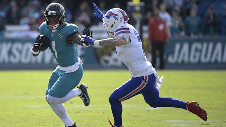 Jan 11, 2026; Jacksonville, FL, USA; Jacksonville Jaguars running back Travis Etienne Jr. (1) runs with the ball against Buffalo Bills cornerback Taron Johnson (7) during the first half in an AFC Wild Card Round game at EverBank Stadium. Mandatory Credit: Melina Myers-Imagn Images