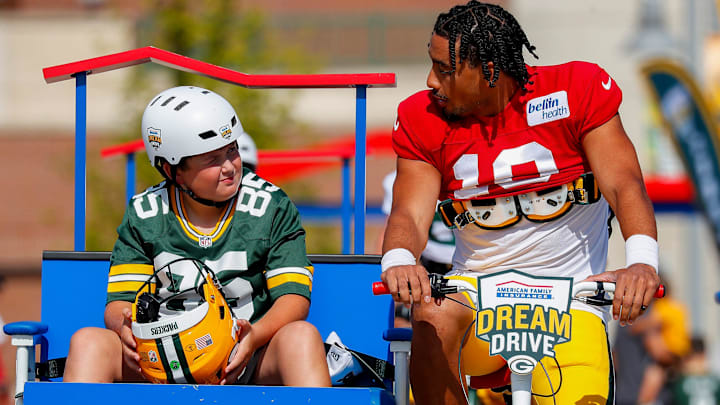 Green Bay Packers quarterback Jordan Love (10) talks with a young fan as they bike to training camp last year.
