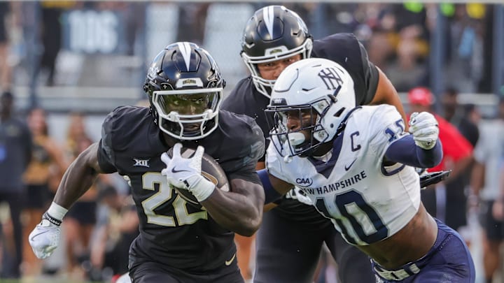 Aug 29, 2024; Orlando, Florida, USA; UCF Knights running back Myles Montgomery (22) runs the ball as New Hampshire Wildcats safety Zedane Williams (10) moves in for the tackle during the first quarter at FBC Mortgage Stadium. Mandatory Credit: Mike Watters-Imagn Images