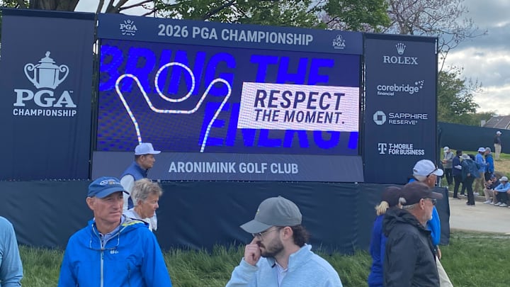 Fans walk past a scoreboard at Aronimink Golf Club during the PGA Championship.
