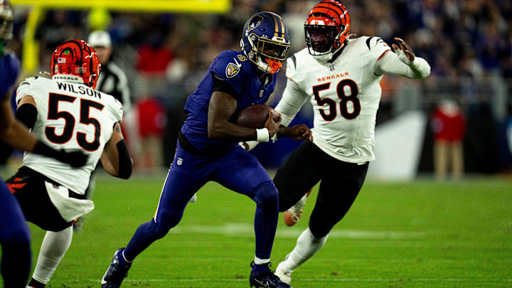 Baltimore Ravens quarterback Lamar Jackson (8) runs downfield for a first down as Cincinnati Bengals linebacker Logan Wilson (55) and Cincinnati Bengals defensive end Joseph Ossai (58) defend in the first quarter of the NFL game at M&T Banks Stadium in Baltimore on Thursday, Nov. 7, 2024.