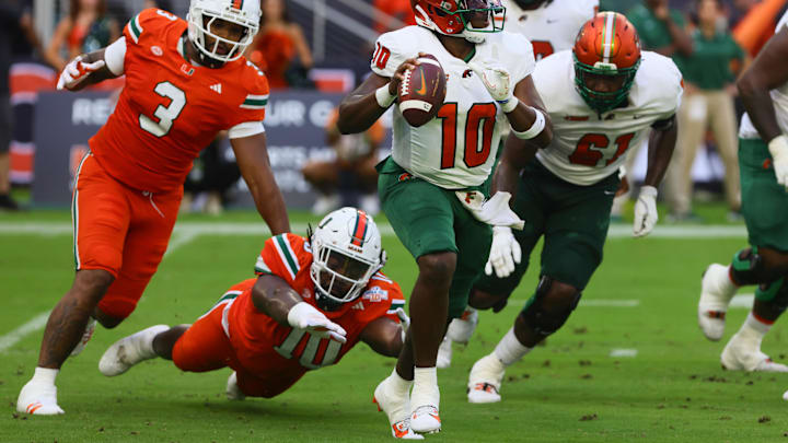 Sep 7, 2024; Miami Gardens, Florida, USA; Florida A&M Rattlers quarterback Daniel Richardson (10) runs with the football past Miami Hurricanes defensive lineman Simeon Barrow Jr. (10) and defensive lineman Akheem Mesidor (3) during the first quarter at Hard Rock Stadium. Mandatory Credit: Sam Navarro-Imagn Images
