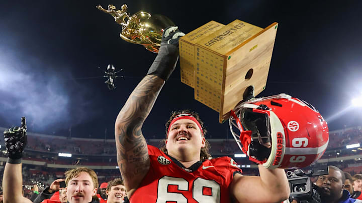 Nov 29, 2024; Athens, Georgia, USA; Georgia Bulldogs offensive lineman Tate Ratledge (69) holds the Governor’s Cup with running back Cash Jones (32) after a victory over the Georgia Tech Yellow Jackets in eight overtimes at Sanford Stadium. Mandatory Credit: Brett Davis-Imagn Images