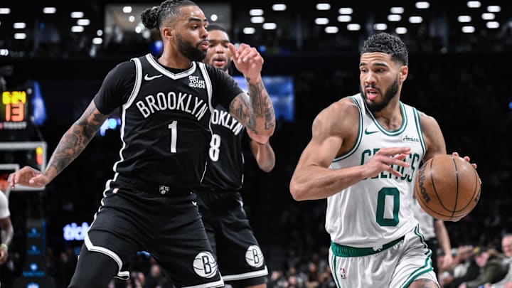 Mar 15, 2025; Brooklyn, New York, USA; Boston Celtics forward Jayson Tatum (0) drives past Brooklyn Nets guard D'Angelo Russell (1) during the second half at Barclays Center. Mandatory Credit: John Jones-Imagn Images