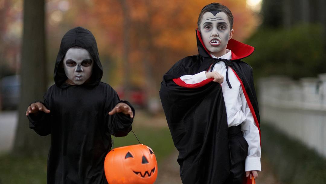 Dos niños (6-7 años) con disfraces de Halloween en la acera, retrato | Christopher Robbins/GettyImages