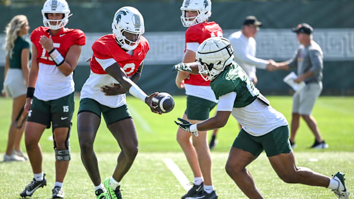 Michigan State's Aidan Chiles, left, hands the ball off to Chris Williams during football practice on Monday, Aug. 11, 2025, in East Lansing.