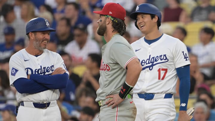 Aug 7, 2024; Los Angeles, California, USA;  Los Angeles Dodgers first base coach Clayton McCullough (86), designated hitter Shohei Ohtani (17) and Philadelphia Phillies first baseman Bryce Harper (3) laugh as they wait for a replay in the first inning at Dodger Stadium. 