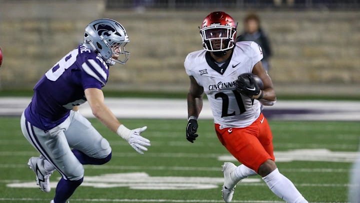 Nov 23, 2024; Manhattan, Kansas, USA; Cincinnati Bearcats running back Corey Kiner (21) runs by Kansas State Wildcats linebacker Rex Van Wyhe (28) during the fourth quarter at Bill Snyder Family Football Stadium. Mandatory Credit: Scott Sewell-Imagn Images Nov 23, 2024; Manhattan, Kansas, USA; Cincinnati Bearcats running back Corey Kiner (21) runs by Kansas State Wildcats linebacker Rex Van Wyhe (28) during the fourth quarter at Bill Snyder Family Football Stadium. Mandatory Credit: Scott Sewell-Imagn Images