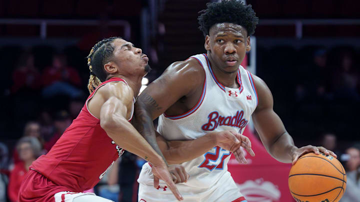 Northern Illinois’ Gianni Cobb collides with Bradley’s Jaquan Johnson in the first half of their college basketball game Saturday, Dec. 6, 2025 at Carver Arena in Peoria. The Braves routed the Huskies 84-55.