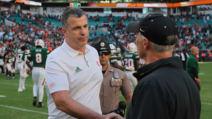 Nov 23, 2024; Miami Gardens, Florida, USA; Miami Hurricanes head coach Mario Cristobal shakes hands with Wake Forest Demon Deacons head coach Dave Clawson after the game at Hard Rock Stadium. Mandatory Credit: Sam Navarro-Imagn Images