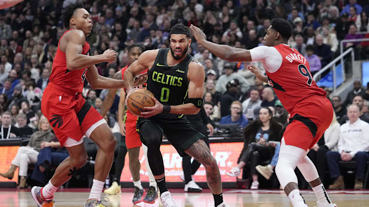 Jan 15, 2025; Toronto, Ontario, CAN; Boston Celtics forward Jayson Tatum (0) drives against Toronto Raptors forward Scottie Barnes (4) and guard RJ Barrett (9) during the first half at Scotiabank Arena. Mandatory Credit: John E. Sokolowski-Imagn Images